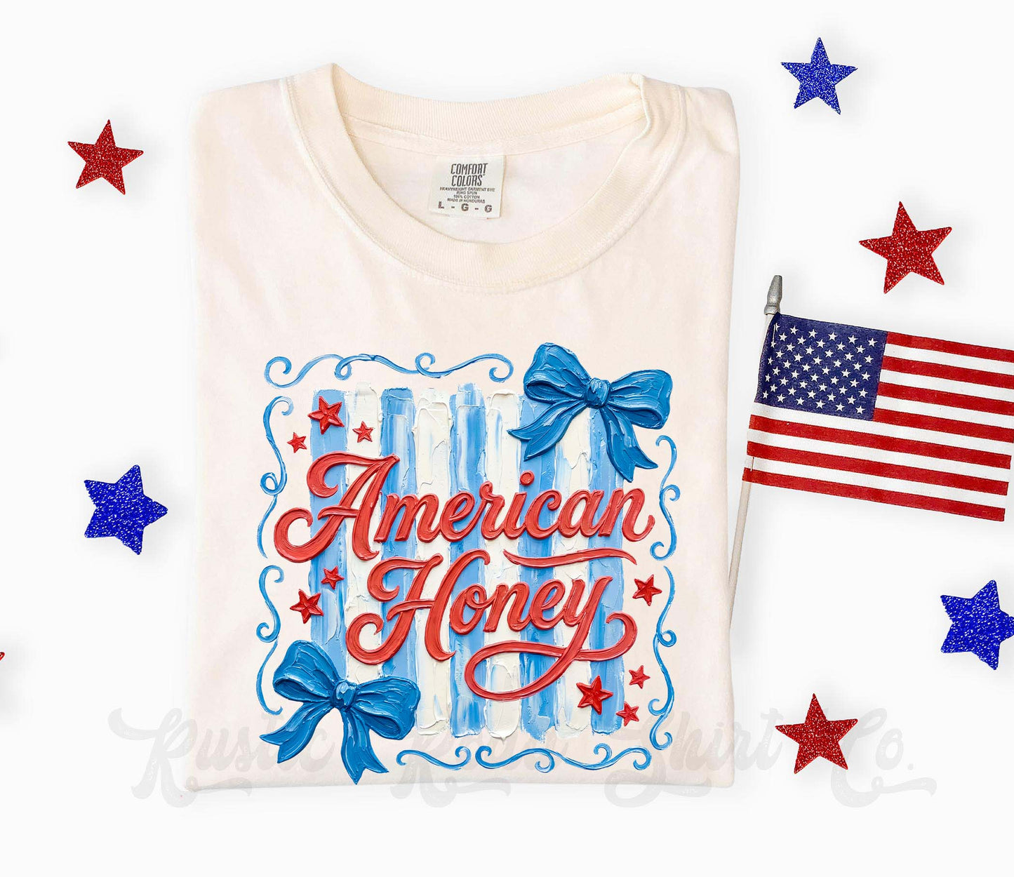 White t-shirt with 'American Honey' design, blue bows, and stars on a white background with American flag and stars.