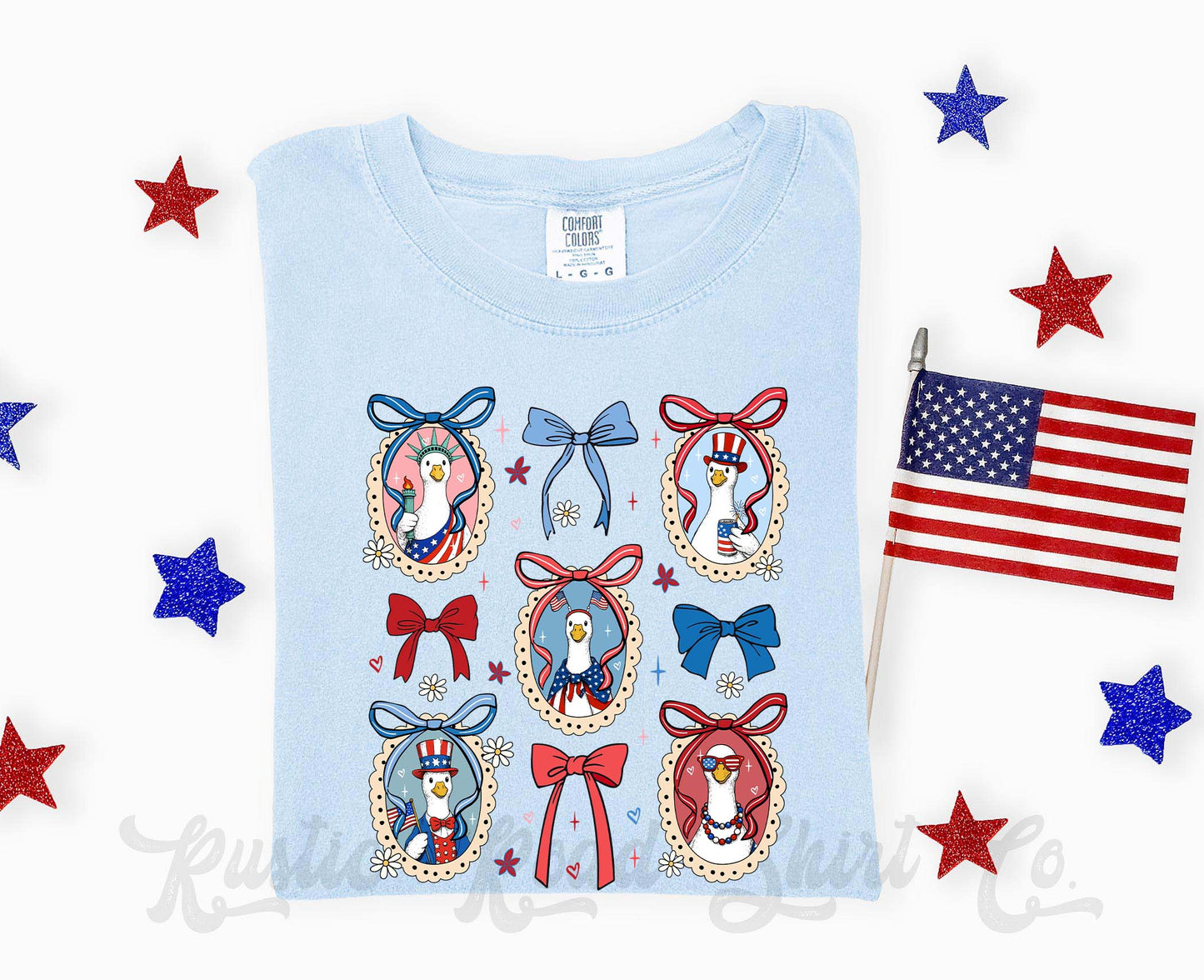 Light blue t-shirt with decorative penguin designs and an American flag on a white background.