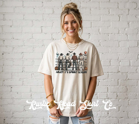 A woman wearing a cream-colored graphic t-shirt with a 'Halloween' character print and the text 'HONOR IT'S SPOKY SCARECROW' stands against a white brick wall. A watermark for 'Krusty Road Shirt Co' is visible at the bottom.
