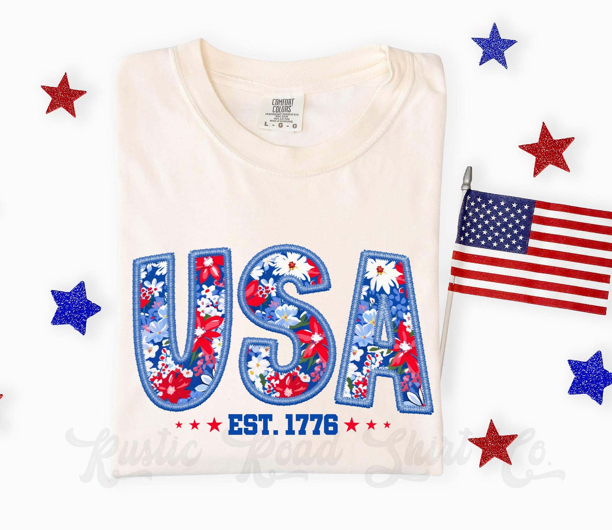 White t-shirt with 'USA' design featuring stars and stripes, surrounded by American flag and stars on a white background.