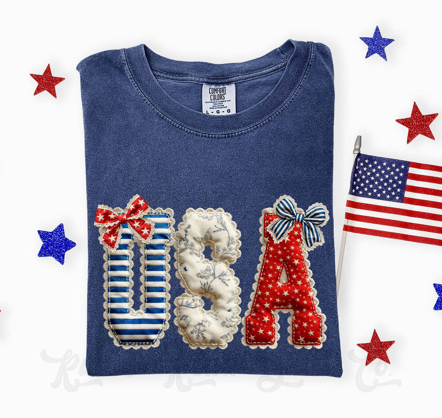 Blue t-shirt with 'USA' design featuring stars and stripes, surrounded by American flags and stars on a white background.